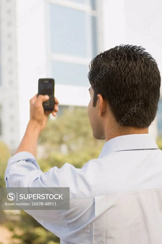 Businessman taking picture of a building from a mobile phone, Gurgaon, Haryana, India