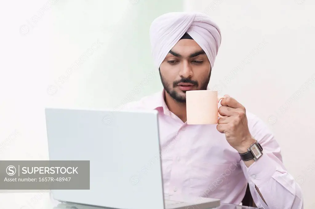 Businessman holding a coffee cup and using a laptop