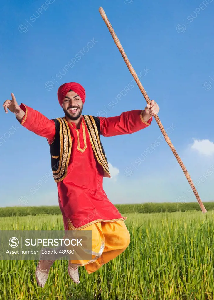 Man doing Bhangra the folk dance of Punjab in India in a field, Gurgaon, Haryana, India