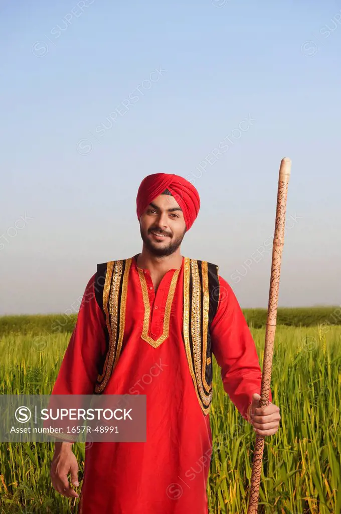Bhangra dancer holding a stick in a field, Gurgaon, Haryana, India