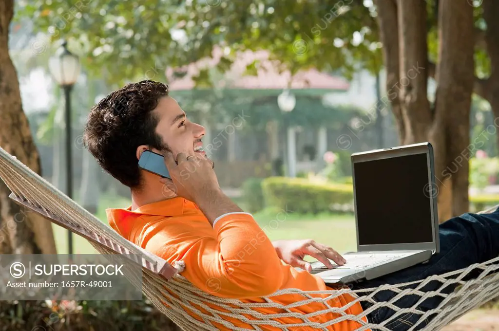 Man talking on a mobile phone in a hammock
