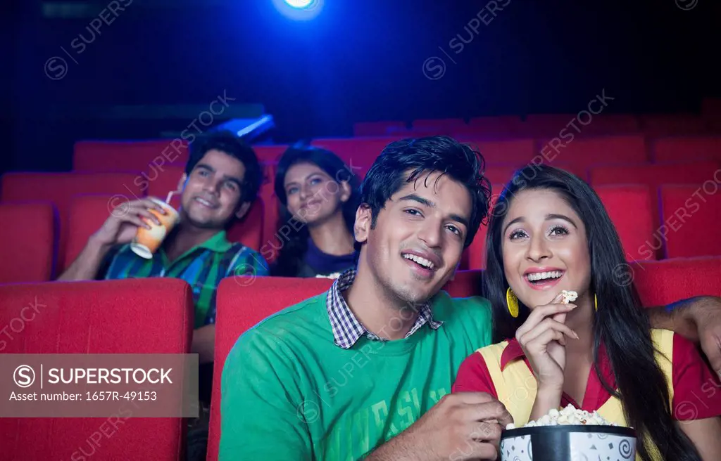 Couple enjoying movie with popcorns in a cinema hall