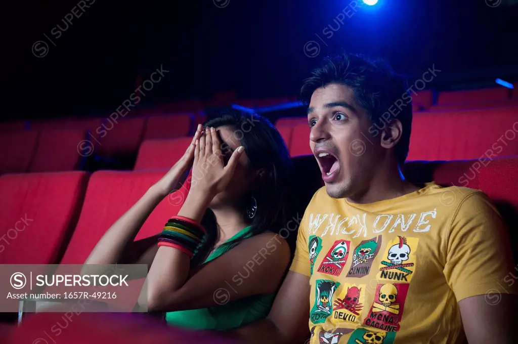 Couple watching movie and looking surprised in a cinema hall