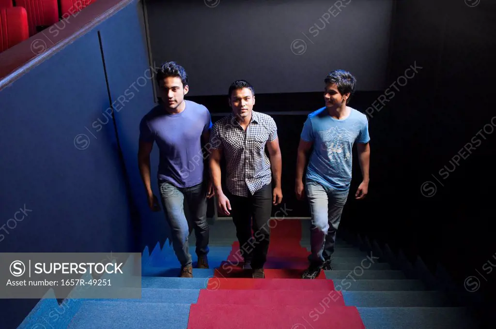 Three friends moving up on steps in a cinema hall