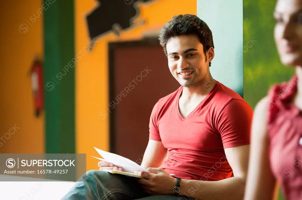 University student sitting with books and smiling