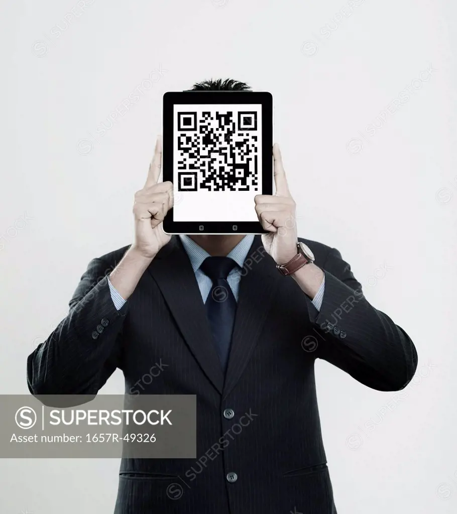 Businessman holding a digital tablet in front of his face with 2D barcode on it