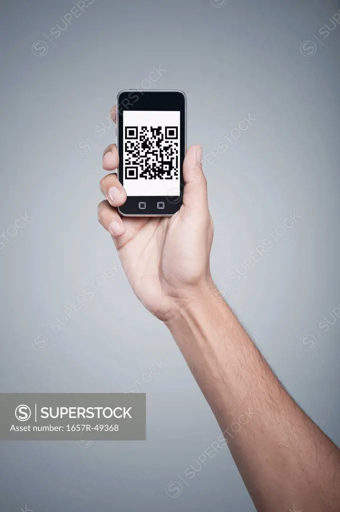 Persons hand holding a mobile phone with 2D Barcode on the screen