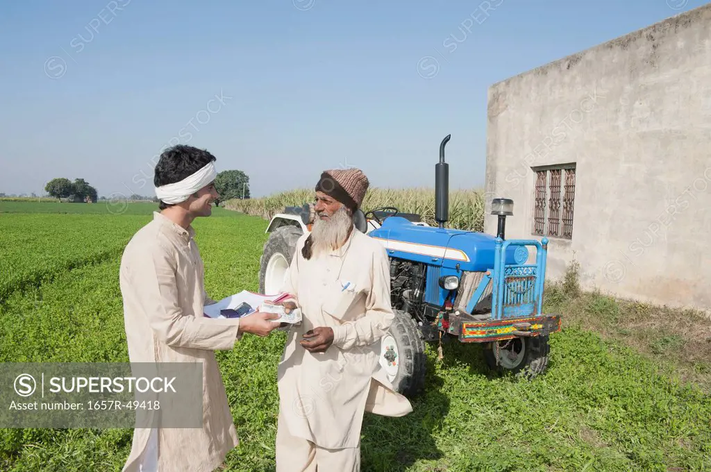 Farmer giving money to another farmer as agriculture loan, Sonipat, Haryana, India