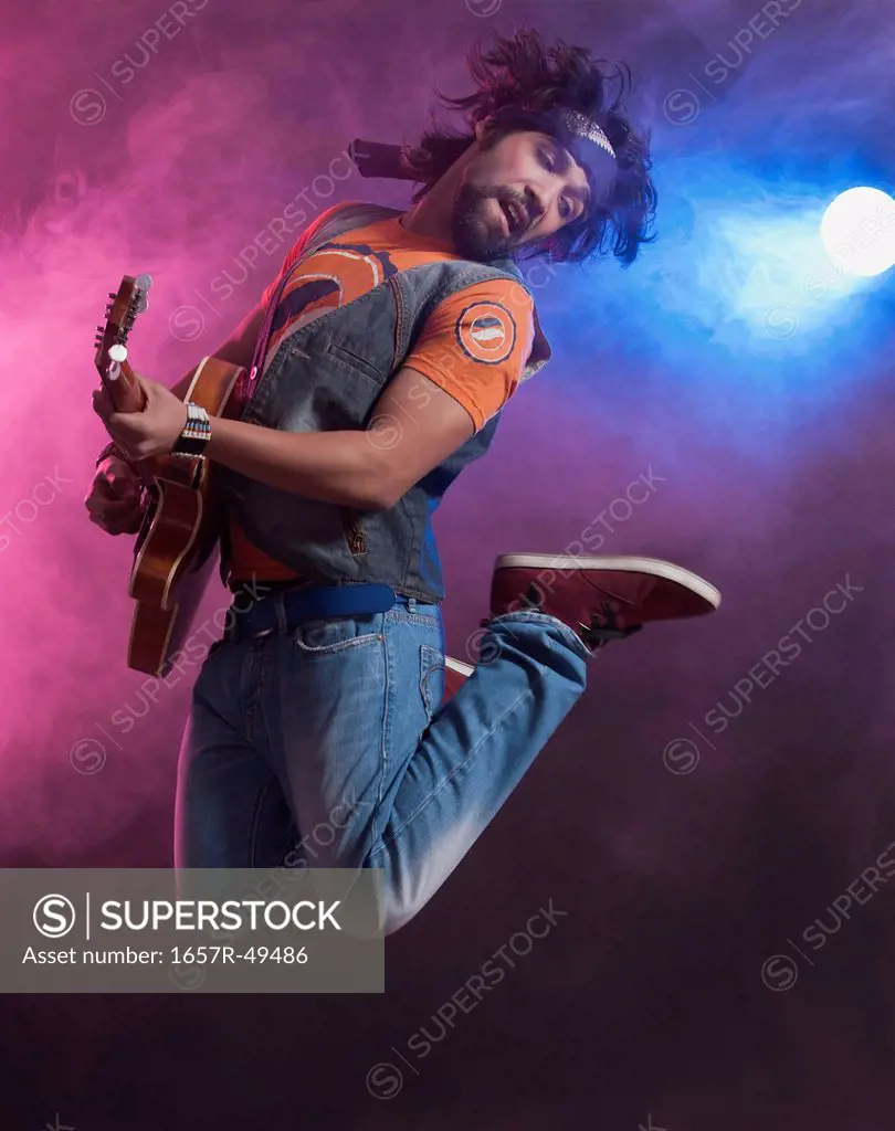 Musician playing a guitar and jumping