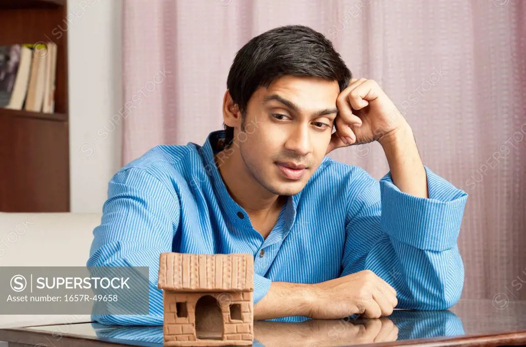 Bengali man looking at a model home and thinking