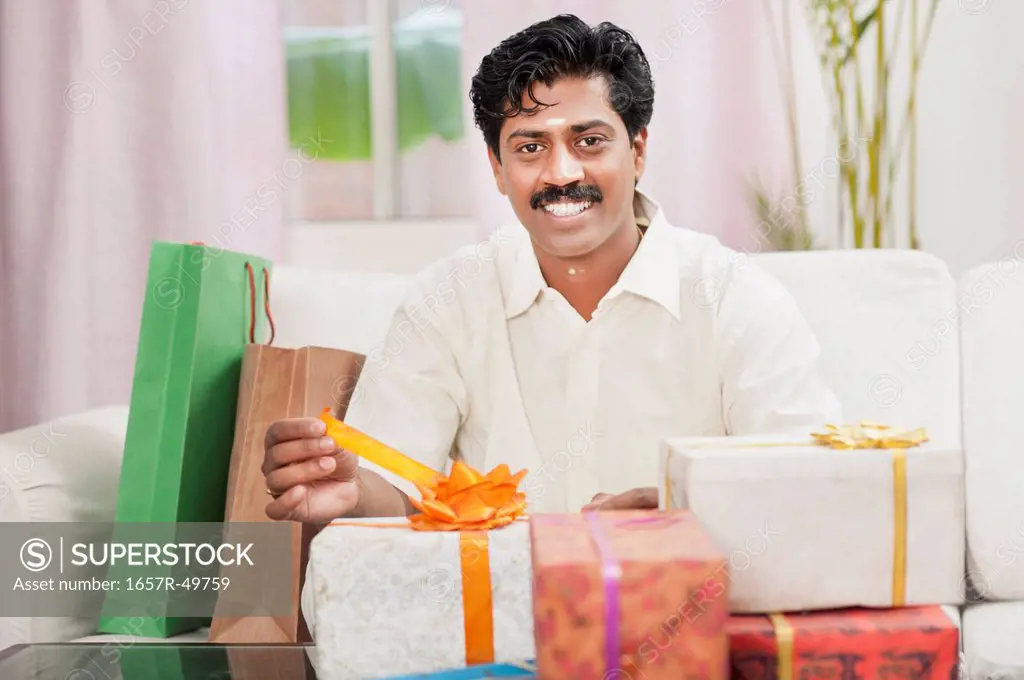 South Indian man smiling near gift boxes