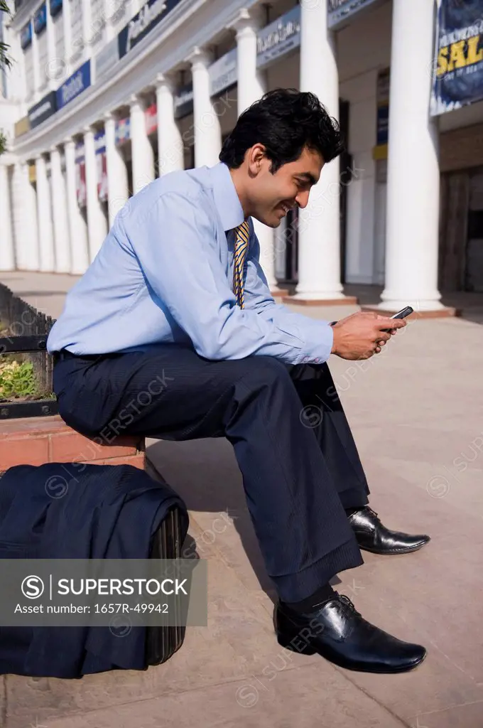 Businessman text messaging on a mobile phone, Gurgaon, Haryana, India
