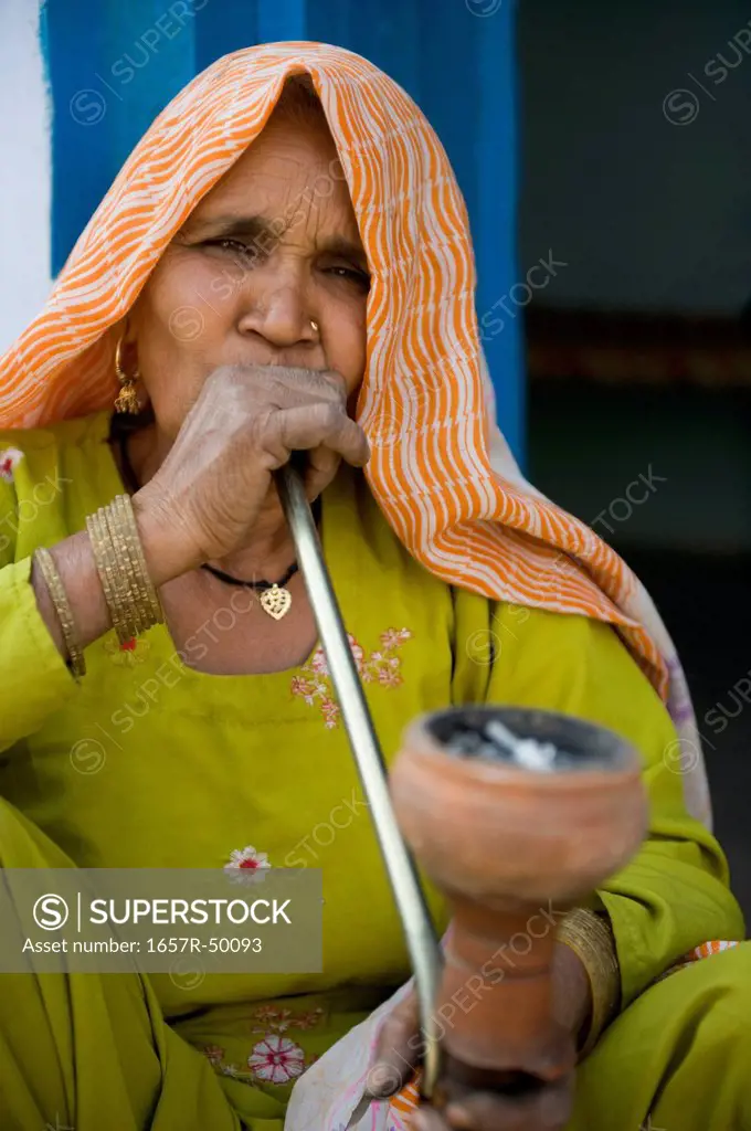Woman smoking a hookah pipe, Farrukh Nagar, Gurgaon, Haryana, India