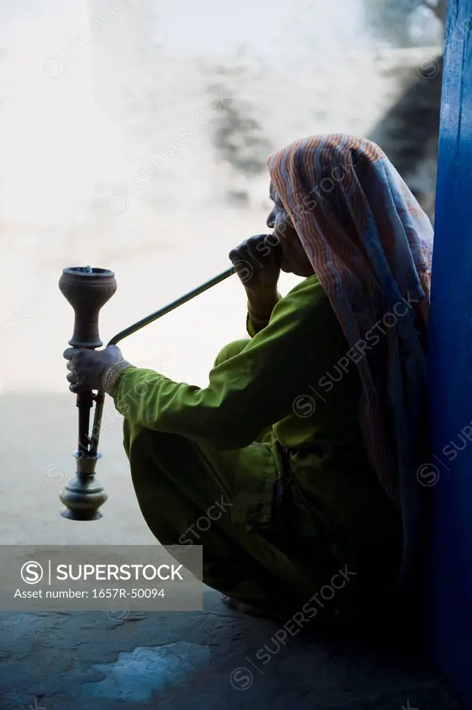 Woman smoking a hookah pipe, Farrukh Nagar, Gurgaon, Haryana, India