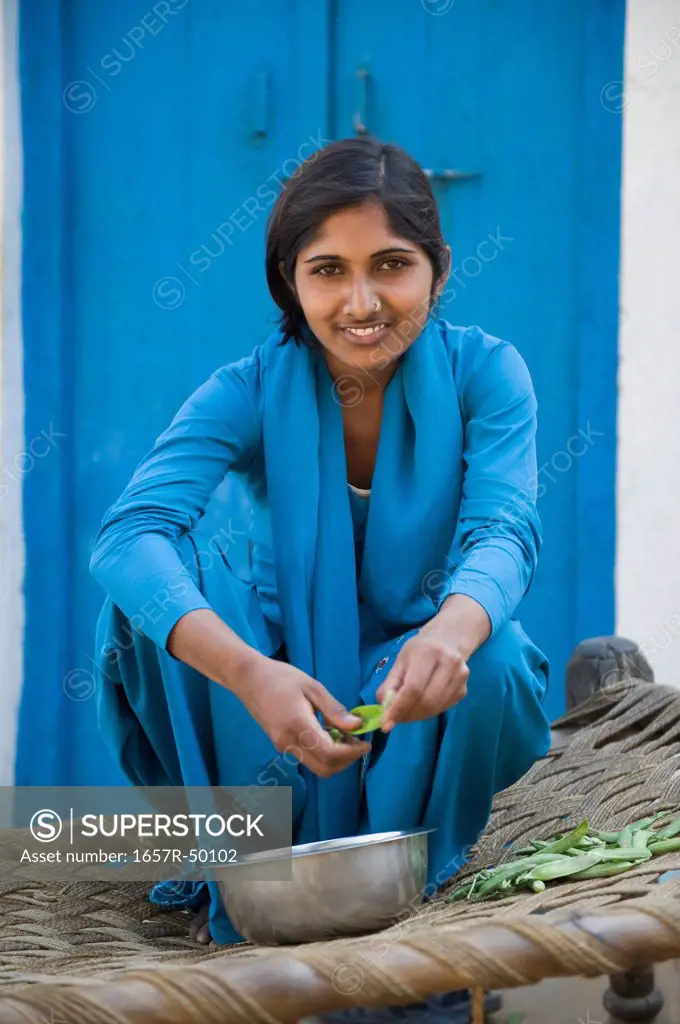 Portrait of a teenage girl shelling green peas, Farrukh Nagar, Gurgaon, Haryana, India