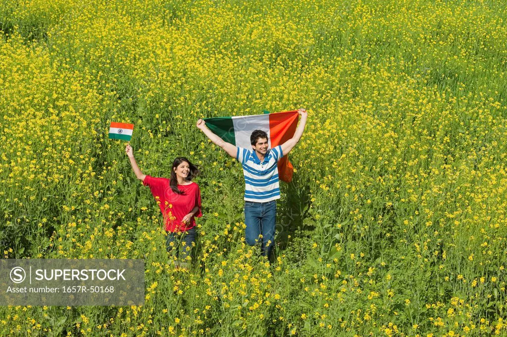 Couple holding an Indian flag and running in an oilseed rape field