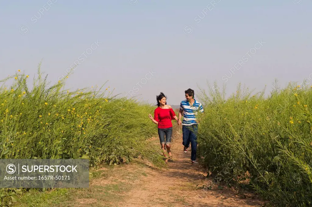 Couple running near an oilseed rape field