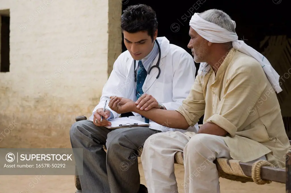 Doctor taking pulse of a farmer, Hasanpur, Haryana, India