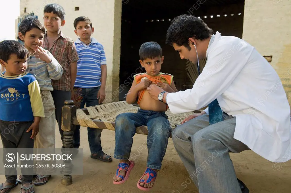 Doctor examining a boy with a stethoscope, Hasanpur, Haryana, India