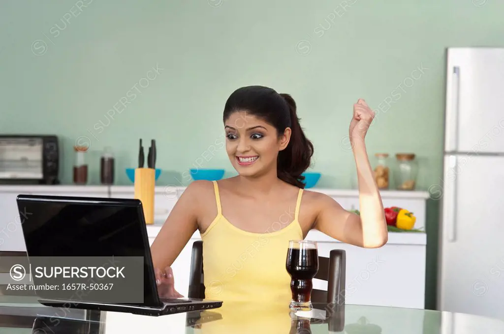 Woman looking at a laptop and celebrating her success, Gurgaon, Haryana, India