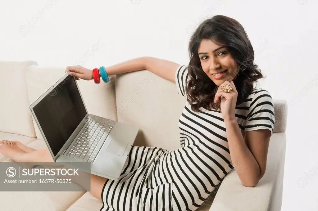 Woman using a laptop and smiling on a couch