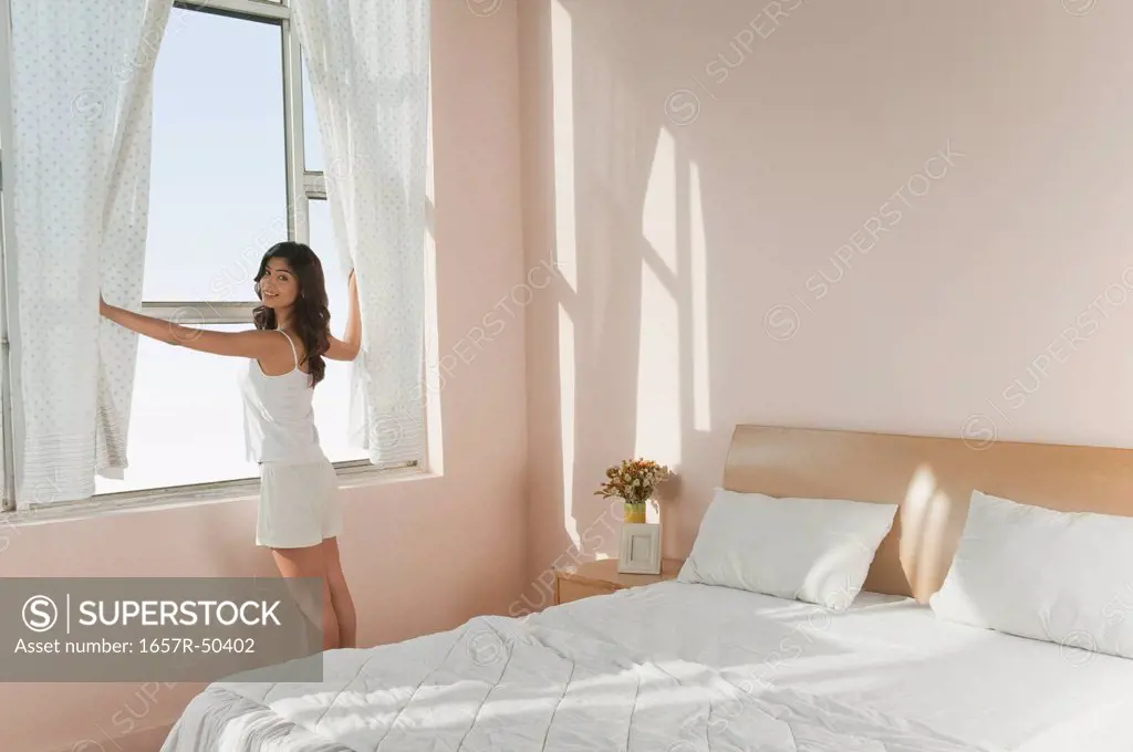 Woman opening curtains of a window