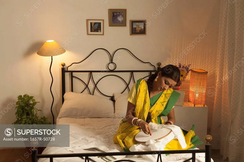 Bengali woman doing embroidery work in the bedroom