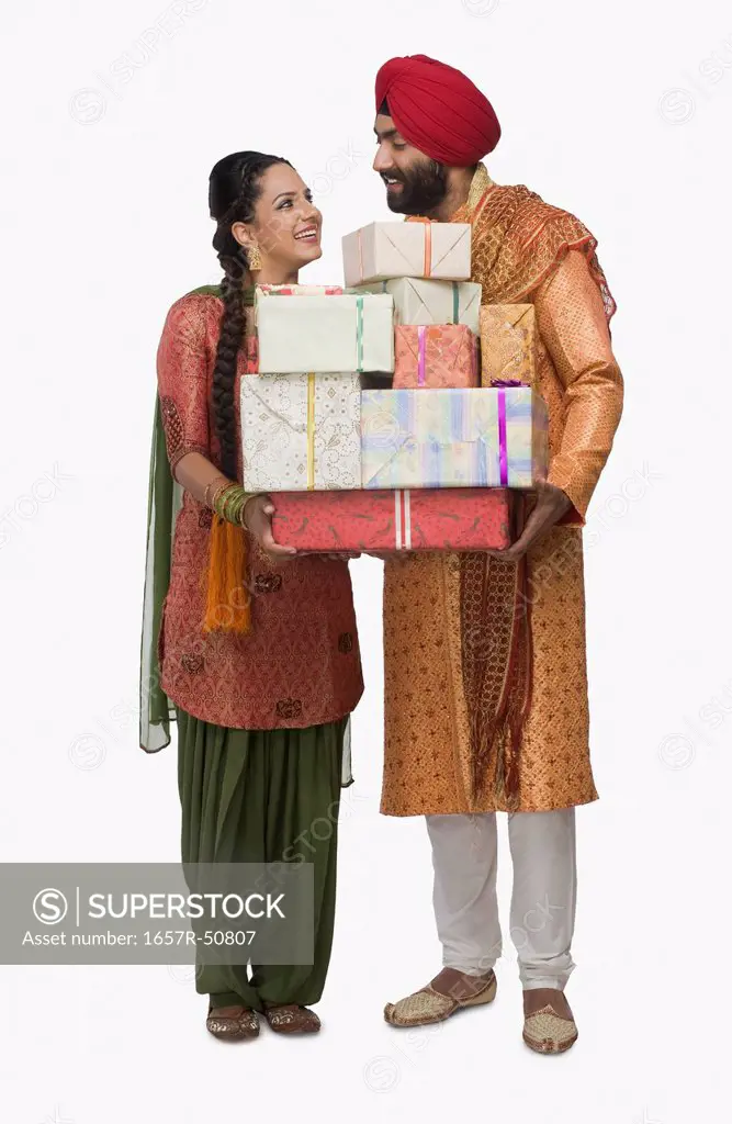 Sikh couple holding stack of presents