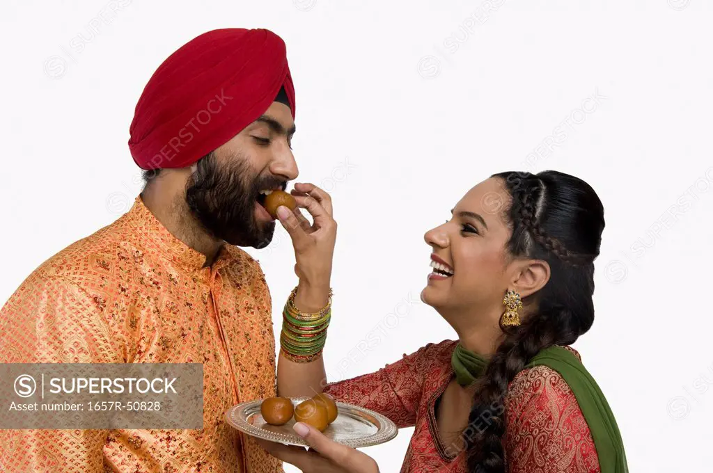Woman feeding gulab jamun to her husband