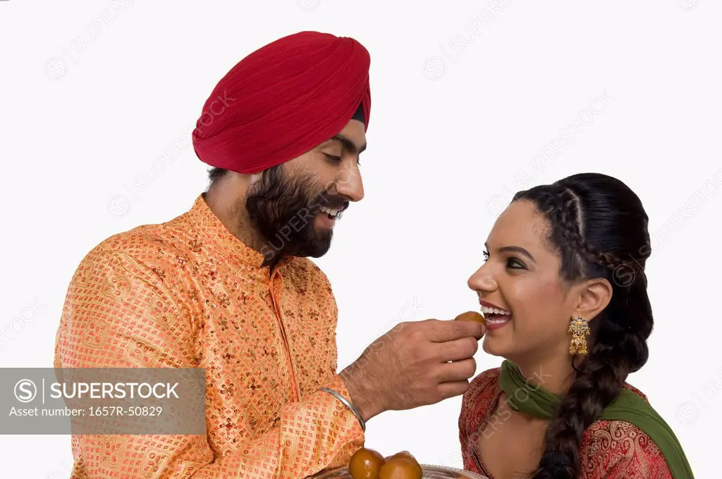 Sikh man feeding gulab jamun to his wife