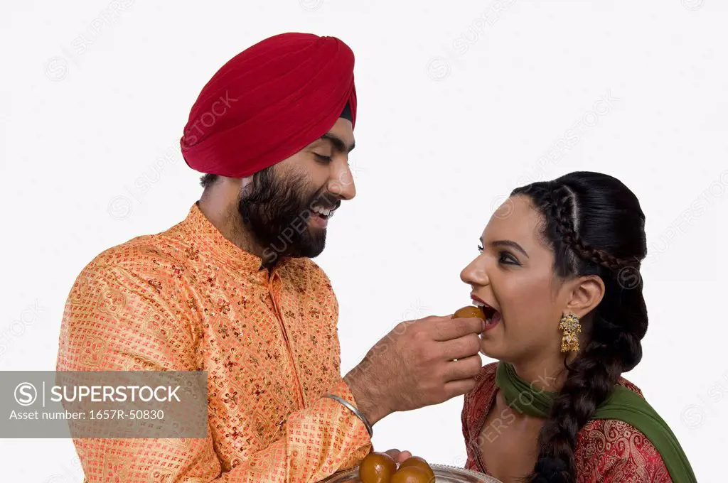 Sikh man feeding gulab jamun to his wife