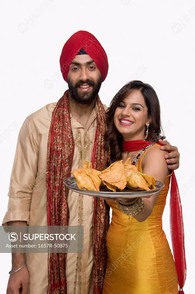 Sikh couple holding a plate of samosa the traditional Indian snack
