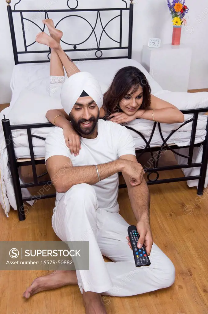 Sikh couple watching TV in the bedroom
