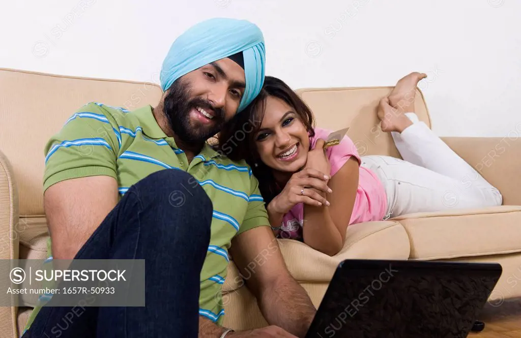 Sikh couple holding credit card and using a laptop