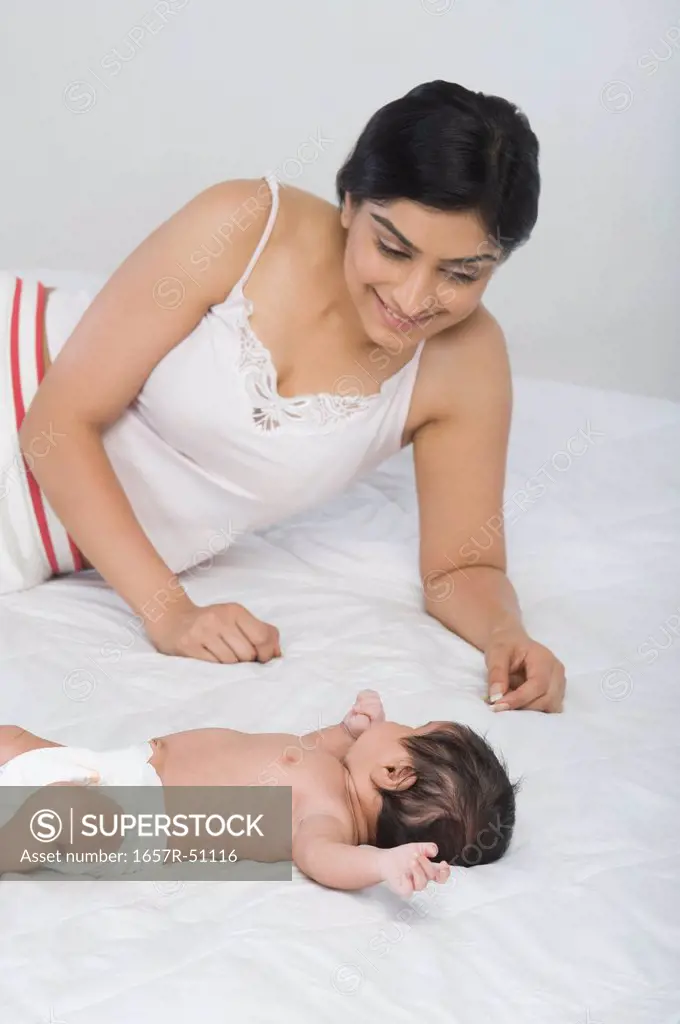 Woman looking at her baby lying on the bed