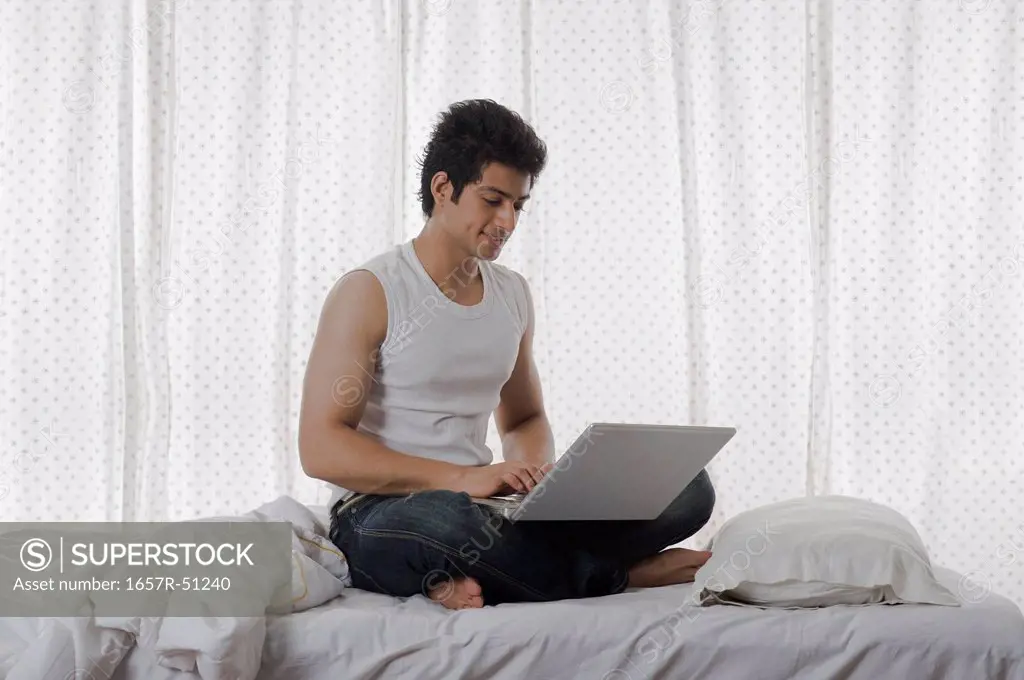 Man using a laptop on the bed