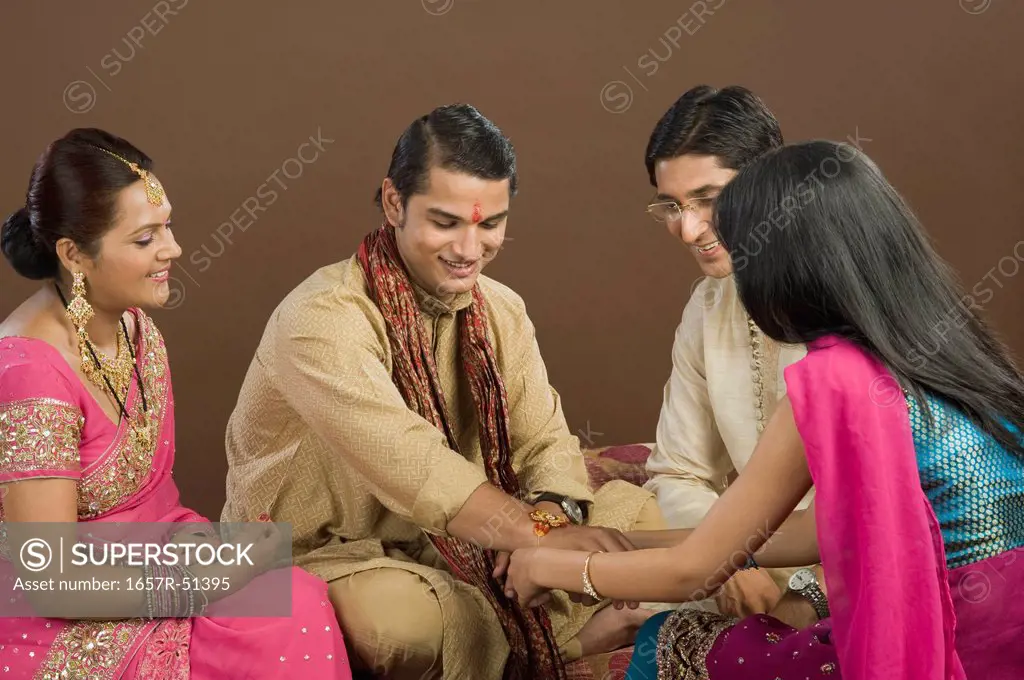 Woman tying rakhi on the wrist of her brother