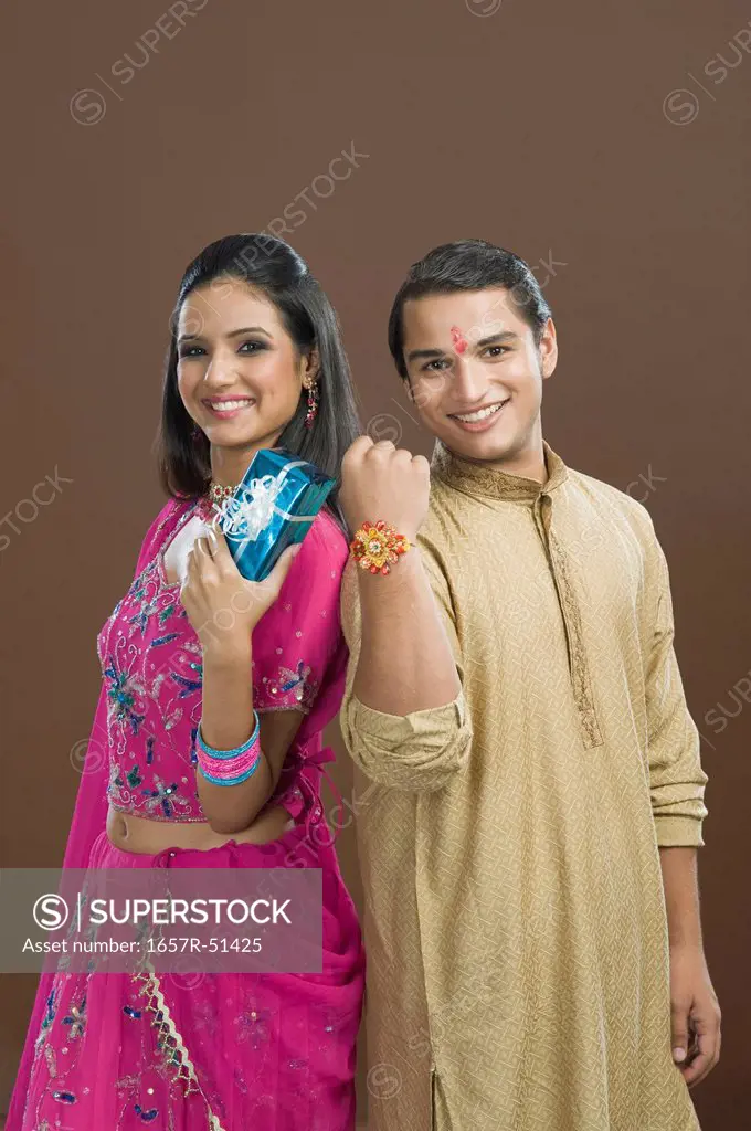 Man showing his rakhi with his sister showing her present
