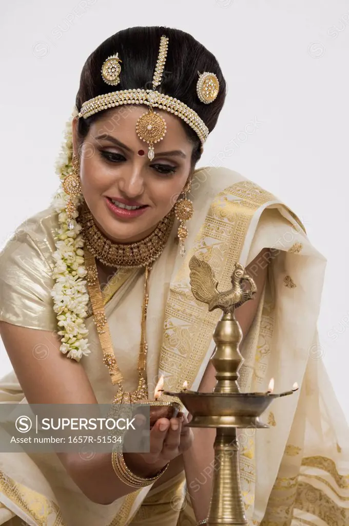Indian woman in traditional clothing lighting an oil lamp