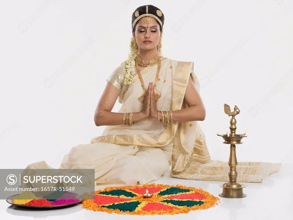 Indian woman in traditional clothing praying at Durga puja festival