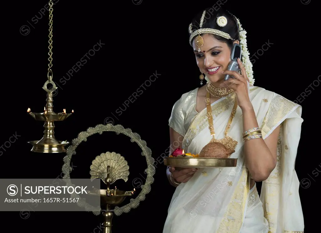 Indian woman in traditional clothing holding religious offering and talking on a mobile phone