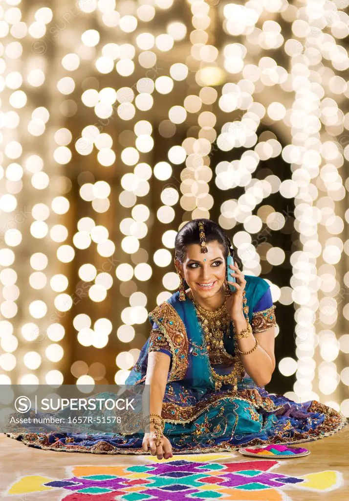 Woman talking on a mobile phone and making rangoli