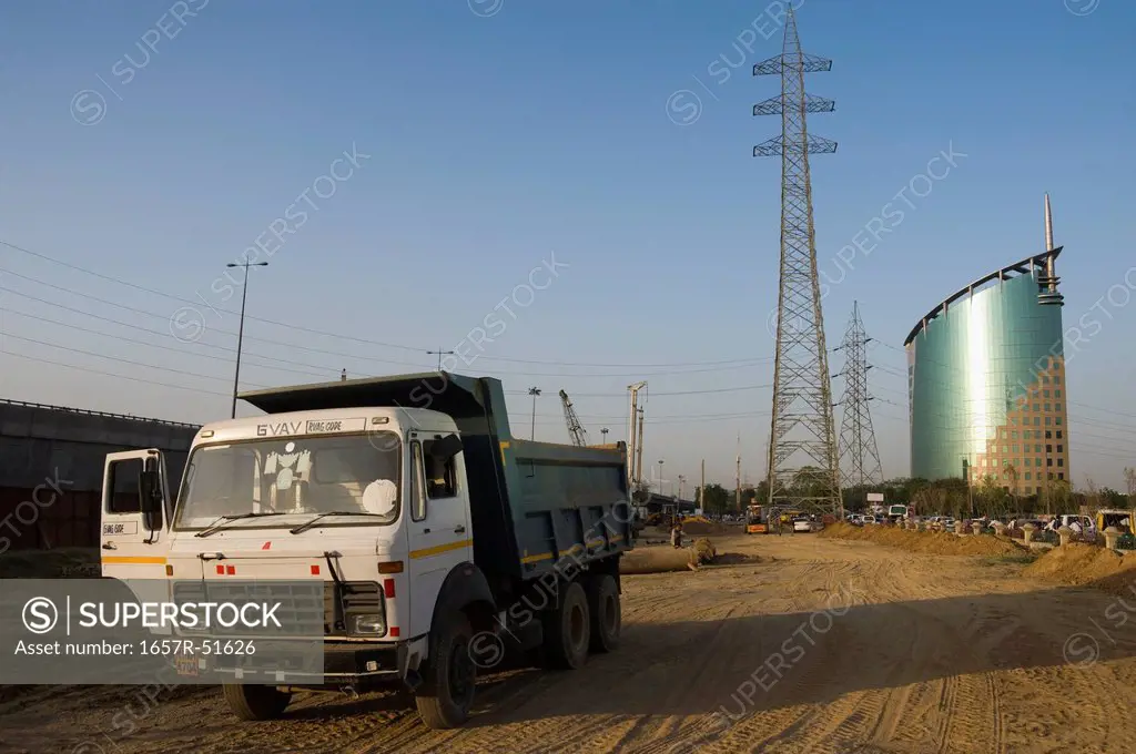 Dump truck on a dirt road with an office building in the background, Gurgaon, Haryana, India