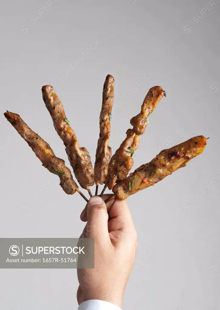Close-up of a person's hand holding kebabs