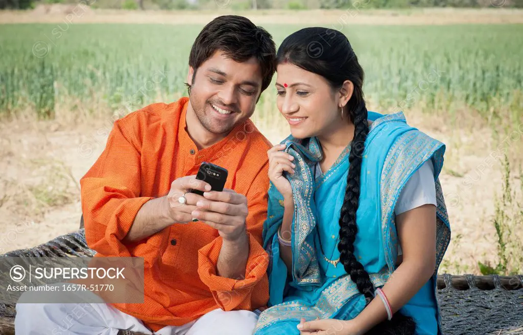 Rural couple text messaging on a mobile phone, Sohna, Haryana, India