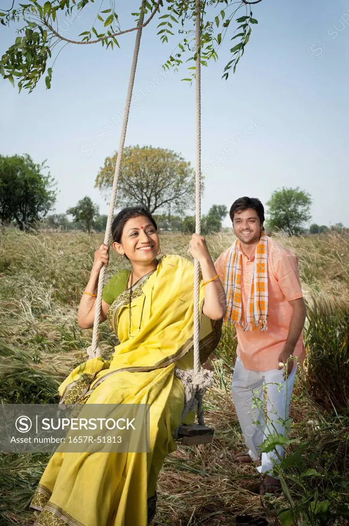 Farmer pushing his wife on a swing in the field, Sohna, Haryana, India