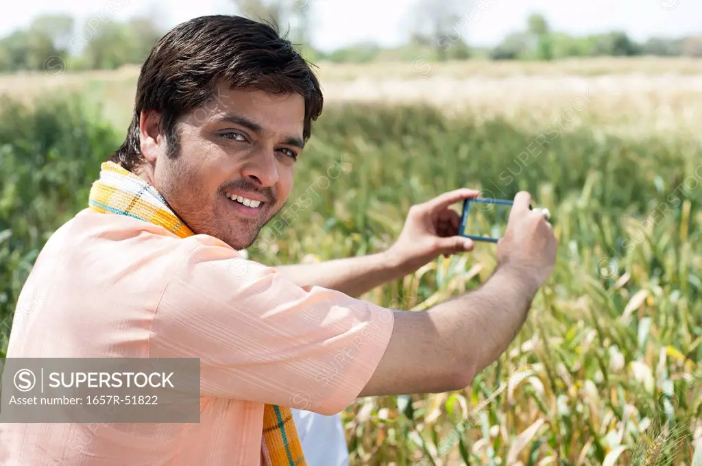 Farmer taking a picture of crop with a mobile phone, Sohna, Haryana, India