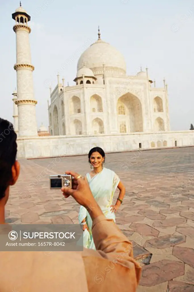 Rear view of a young man taking a photograph of a young woman in front of a mausoleum, Taj Mahal, Agra, Uttar Pradesh, India