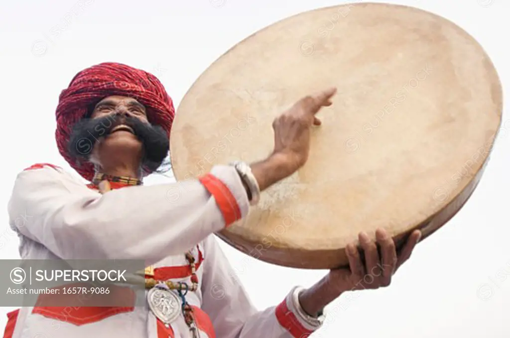 Low angle view of a mature man playing a drum, Elephant Festival, Jaipur, Rajasthan, India