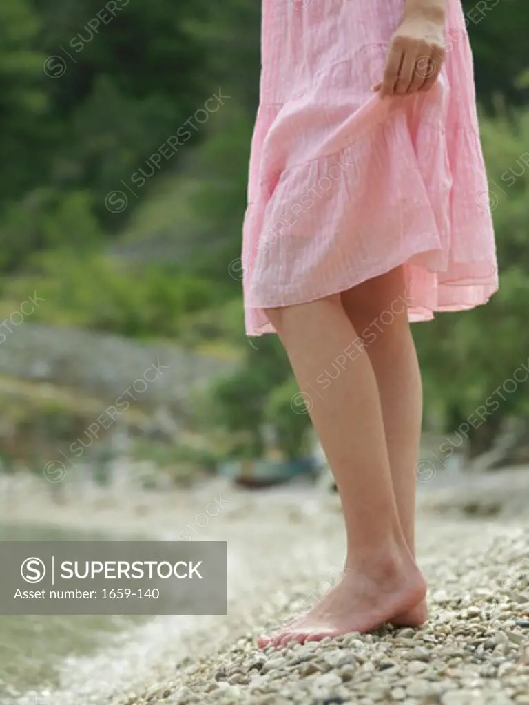 Low section view of a young woman standing on the beach